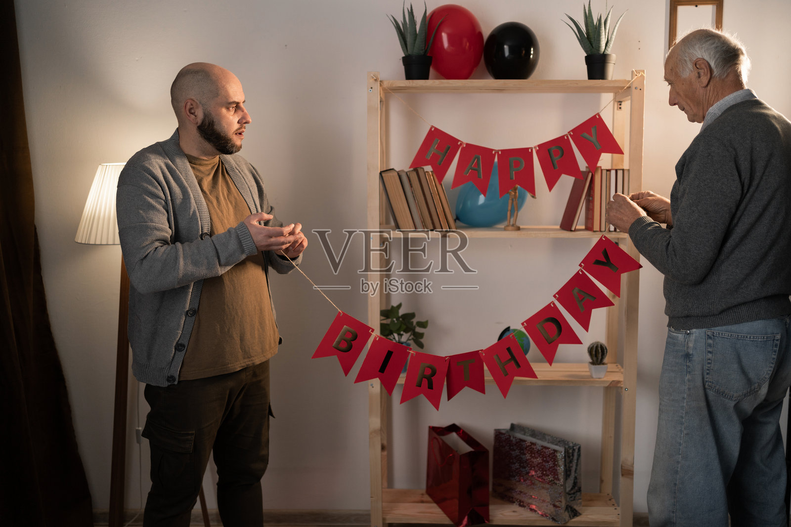 老父亲和成年儿子一起准备节日装饰，制作贺卡纸花环，传承家庭传统。照片摄影图片