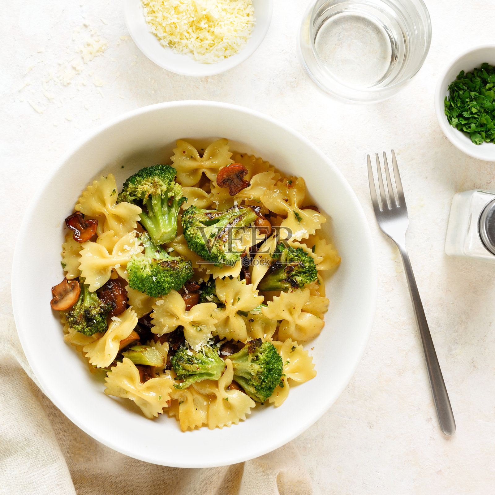 碗中盛有烤西兰花和蘑菇的蝴蝶面意大利面照片摄影图片