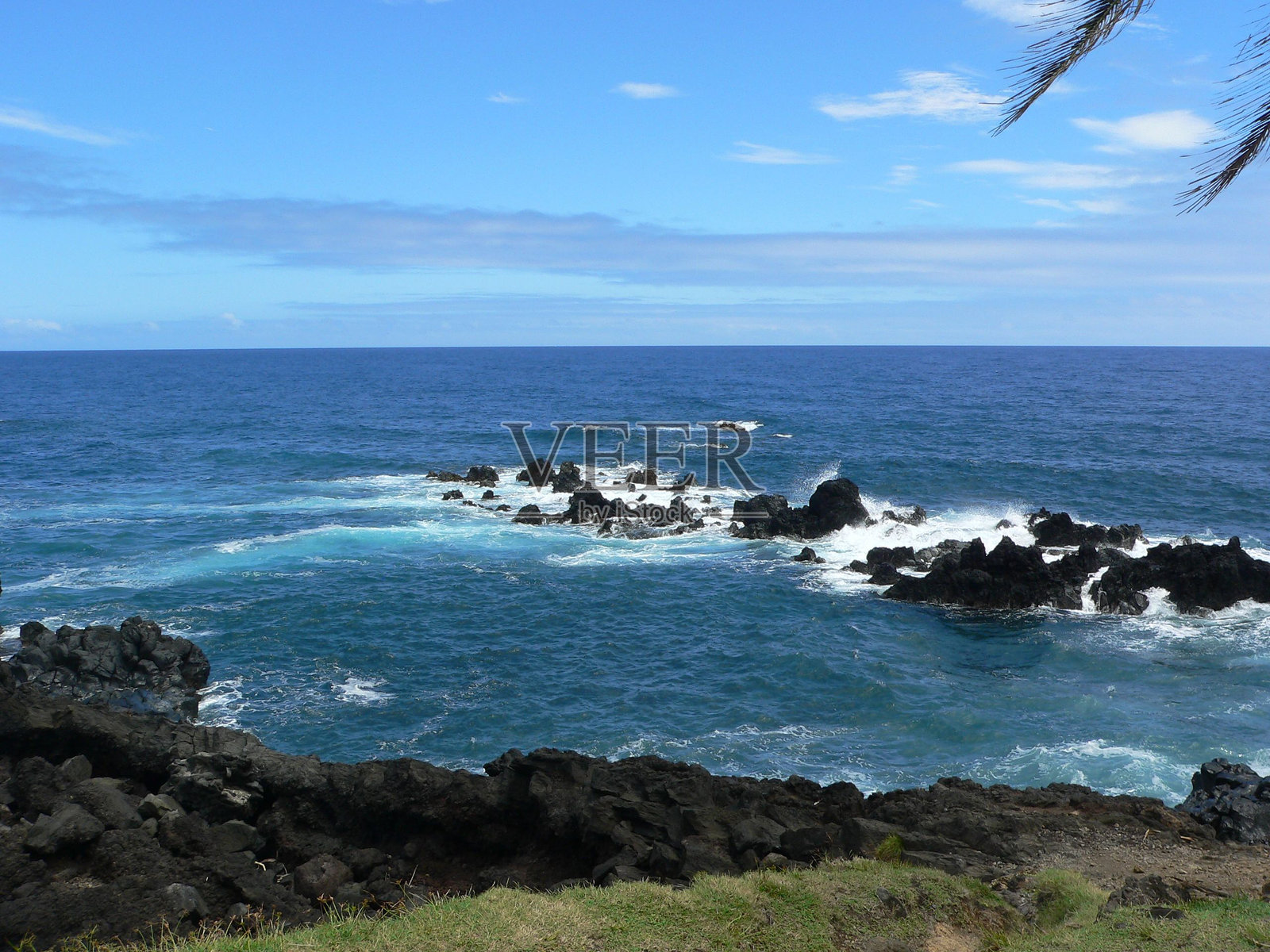 清澈蓝天下，岩石海岸的美丽景色，海浪拍打着岸边。照片摄影图片