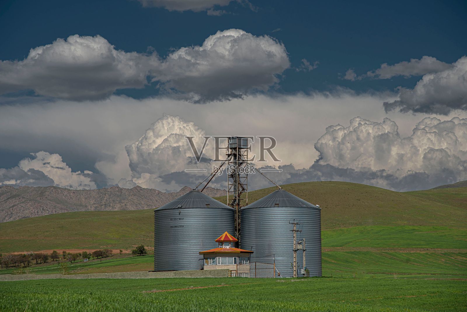 绿色田野中的筒仓与戏剧性的云彩照片摄影图片