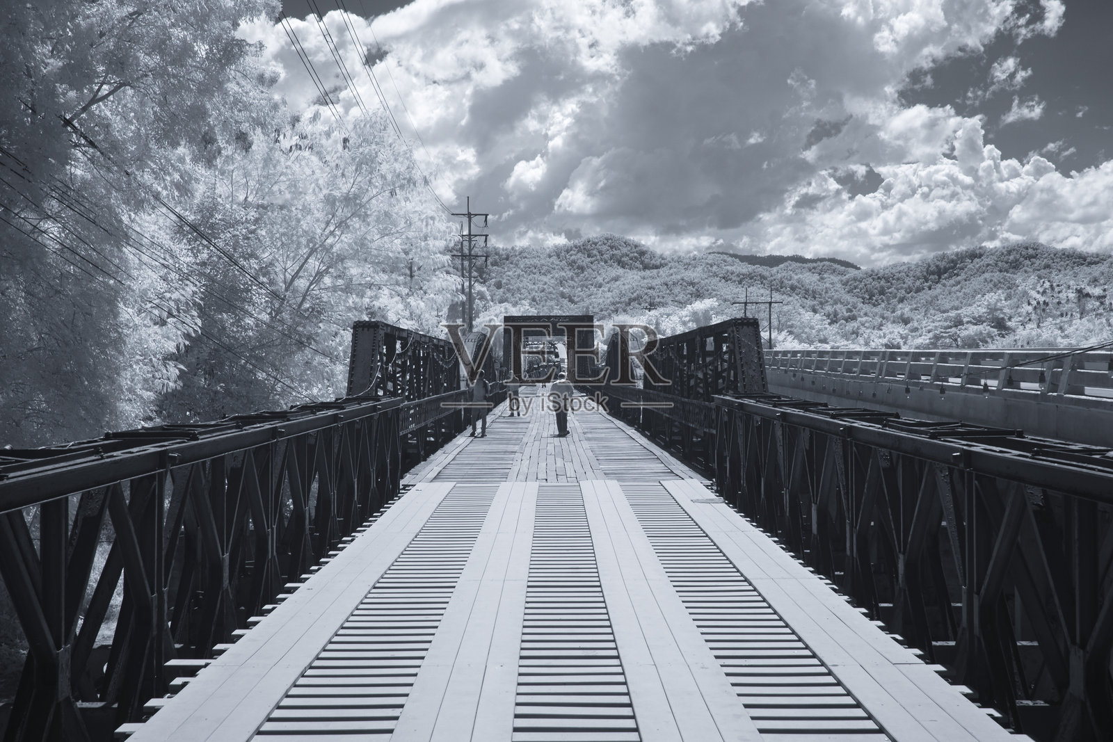 红外摄影，长长的狭窄桥梁延伸至远方，木板铺成的道路位于泰国兰帕干的黑桥上照片摄影图片