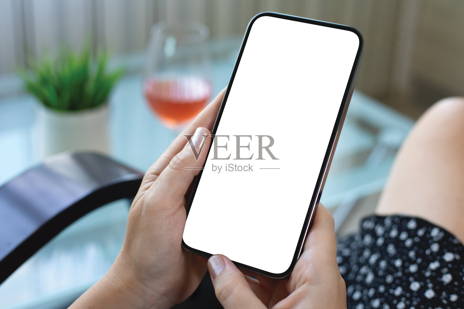 女性手握着手机，背景是玻璃酒杯的空白屏幕照片摄影图片