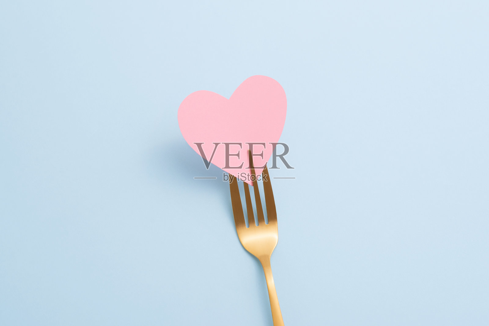 从上方看金色叉子与粉色纸心在淡蓝色背景上。简约的情人节晚餐邀请卡，从上方看。照片摄影图片