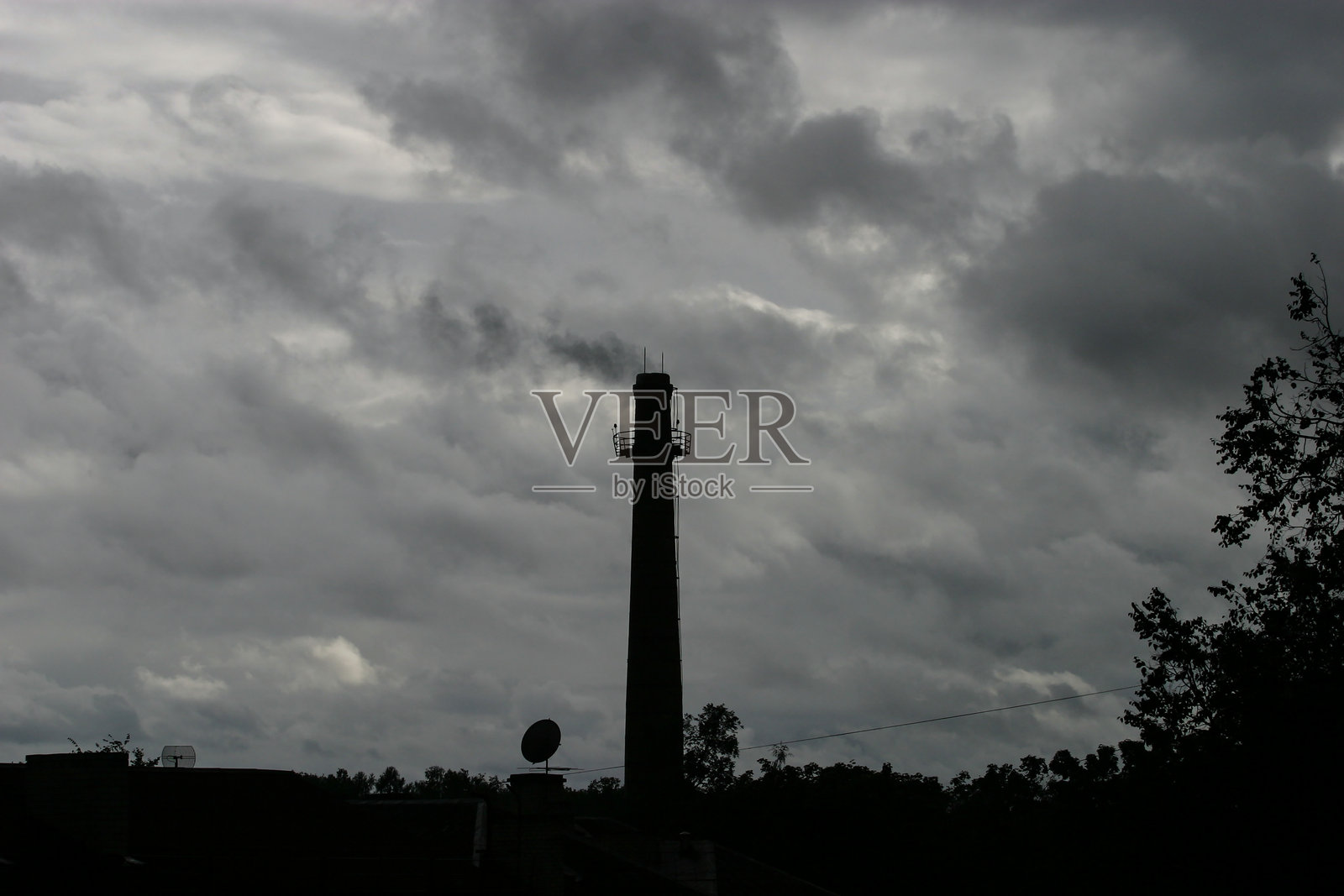 工业烟囱的剪影映衬在阴沉的天空下照片摄影图片