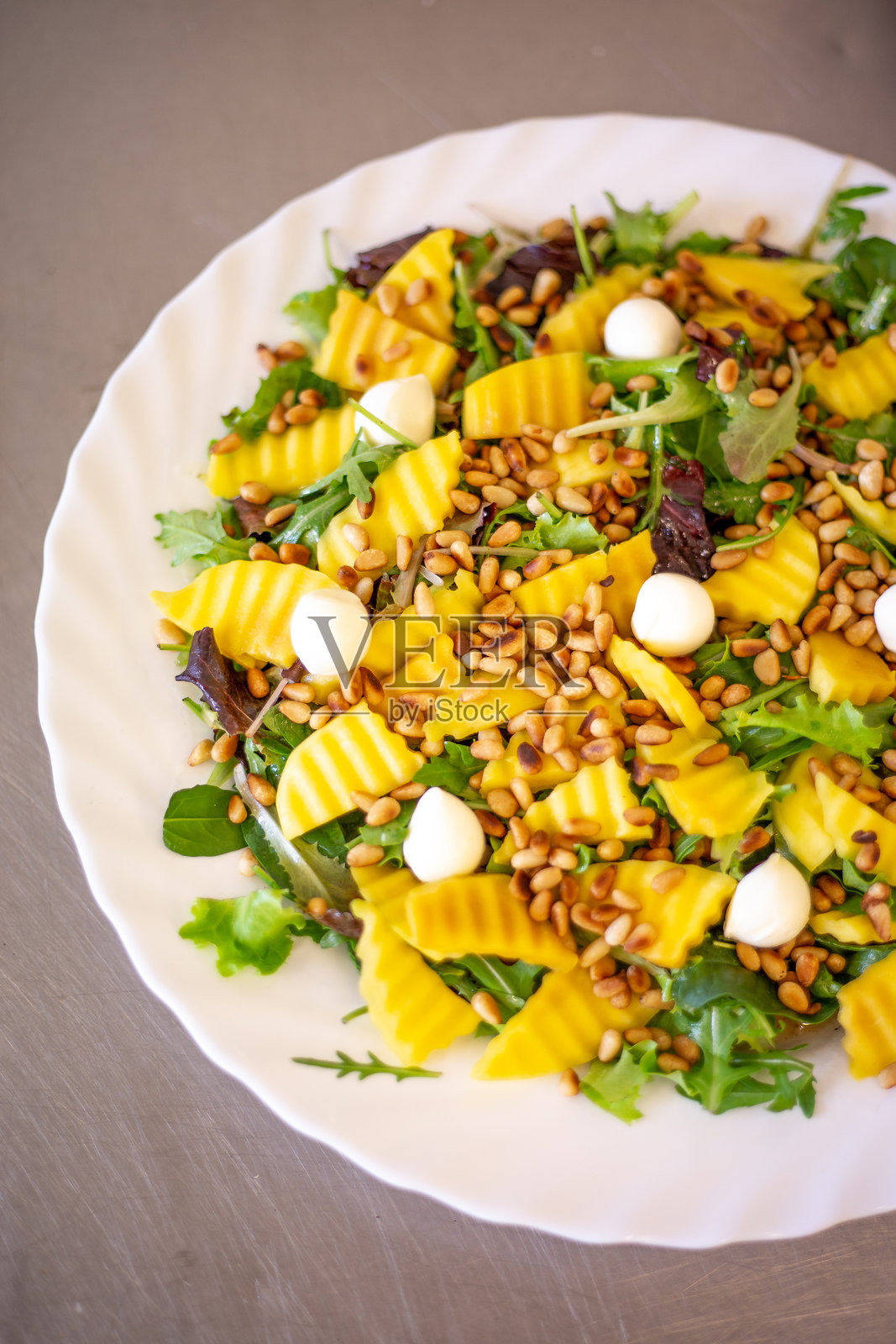 色彩缤纷的沙拉，配有芒果、马苏里拉奶酪和绿叶蔬菜，盛放在盘子上照片摄影图片