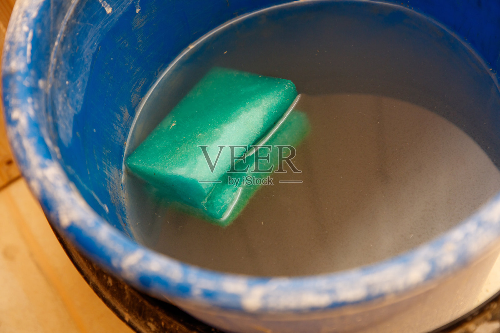 一个装满水的蓝色桶和一个绿色海绵照片摄影图片