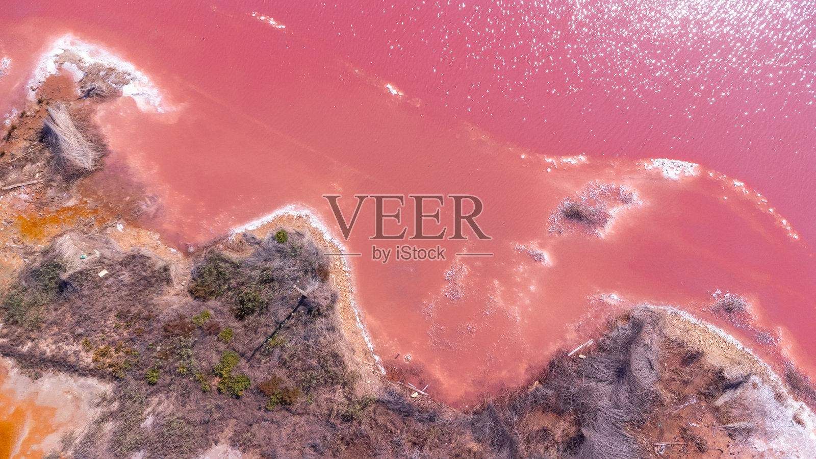 西班牙阿利坎特的托雷维耶哈粉色湖泊在日落时分反射阳光，旁边是盐矿。照片摄影图片