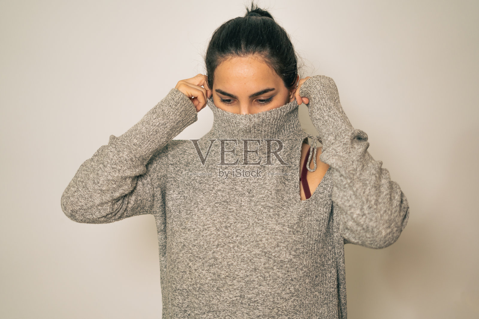 年轻女性调整她的舒适灰色毛衣的肖像照片摄影图片