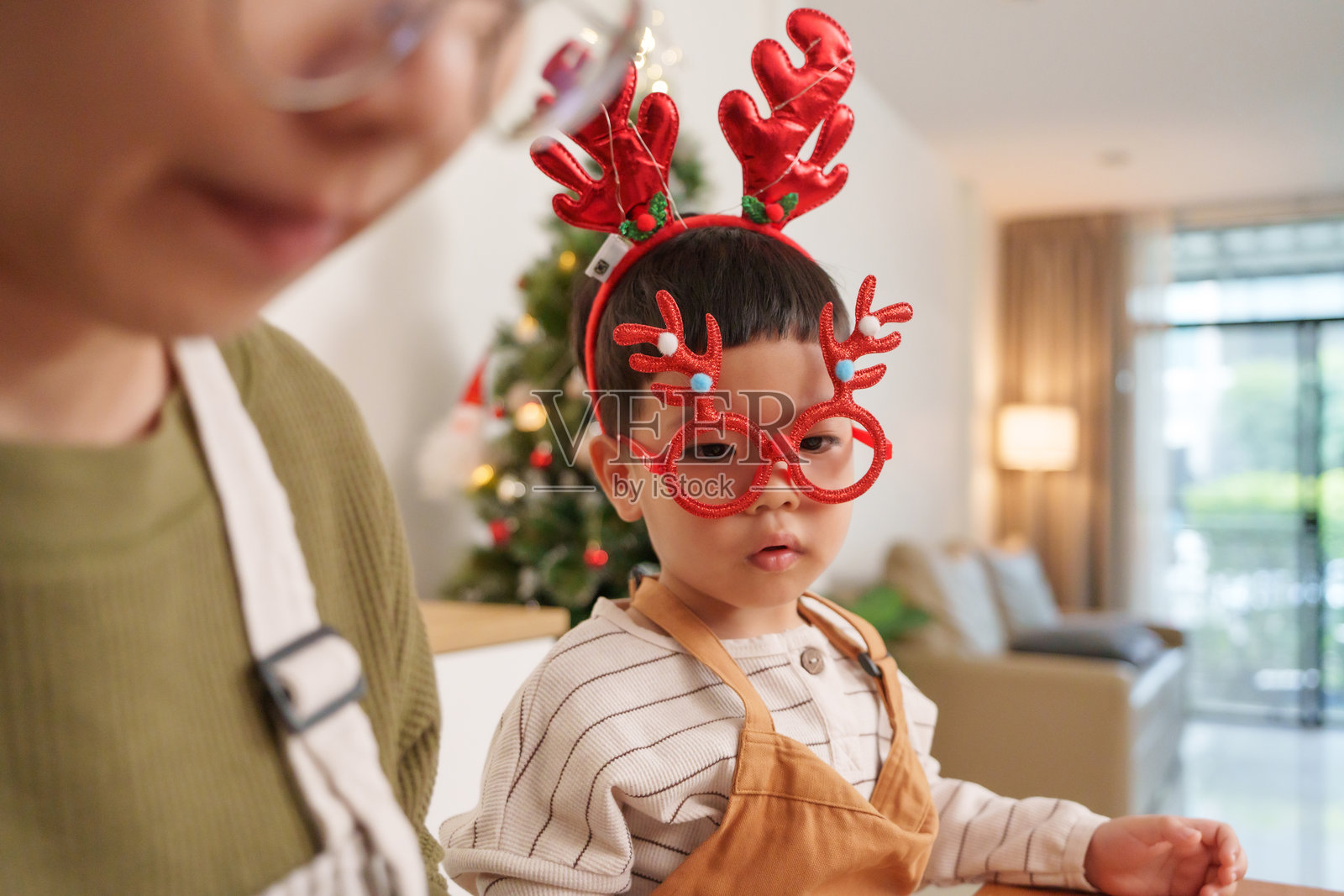 亚洲女性和一个孩子在装饰节日布朗尼，厨房里布置得美丽，充满了圣诞装饰。他们分享这个假日活动，烘焙的快乐显而易见。照片摄影图片