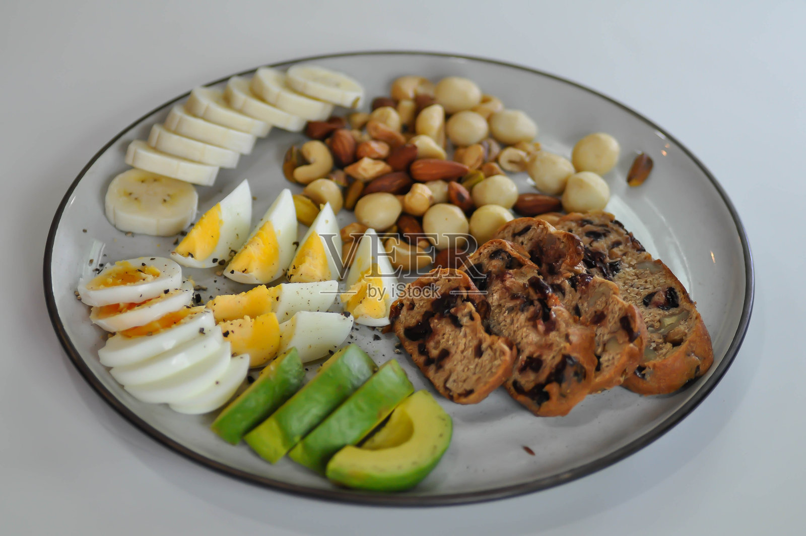 核桃蔓越莓酸面包或蔓越莓酸面包配煮蛋、鳄梨、香蕉和坚果照片摄影图片