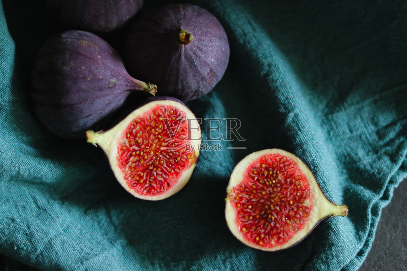 新鲜成熟的无花果特写，置于绿色布料上，伴有深色阴影。照片摄影图片