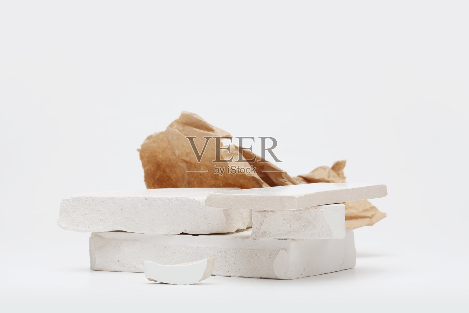 灰色浅色背景上的堆叠石头平台讲台和牛皮纸。极简空旷的产品展示场景。照片摄影图片