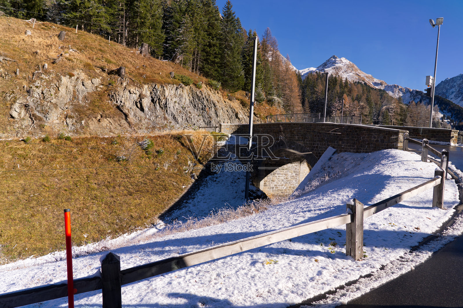 瑞士山口的阿尔卑斯风光，狭轨铁路阿尔布拉的轨迹在阳光明媚的秋日雪景中。照片摄影图片
