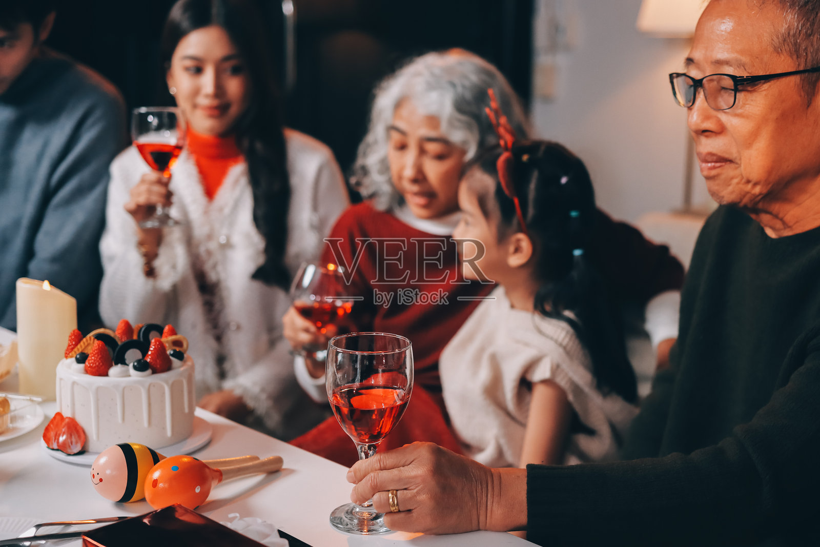 多代家庭在家庆祝圣诞节，戴着圣诞老人帽和鹿角，拆开礼物照片摄影图片