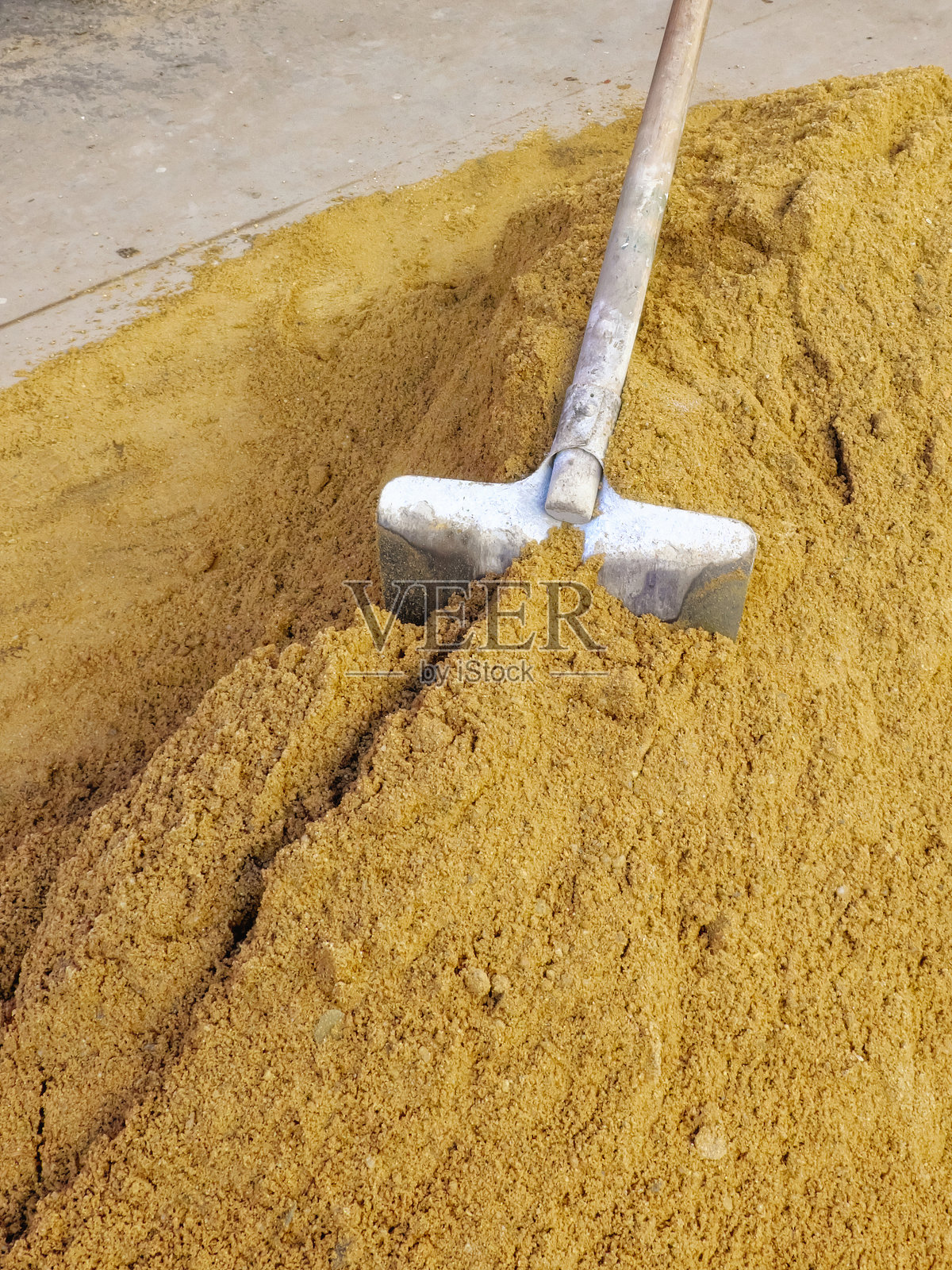 一把铲子插在一堆沙子里。照片摄影图片