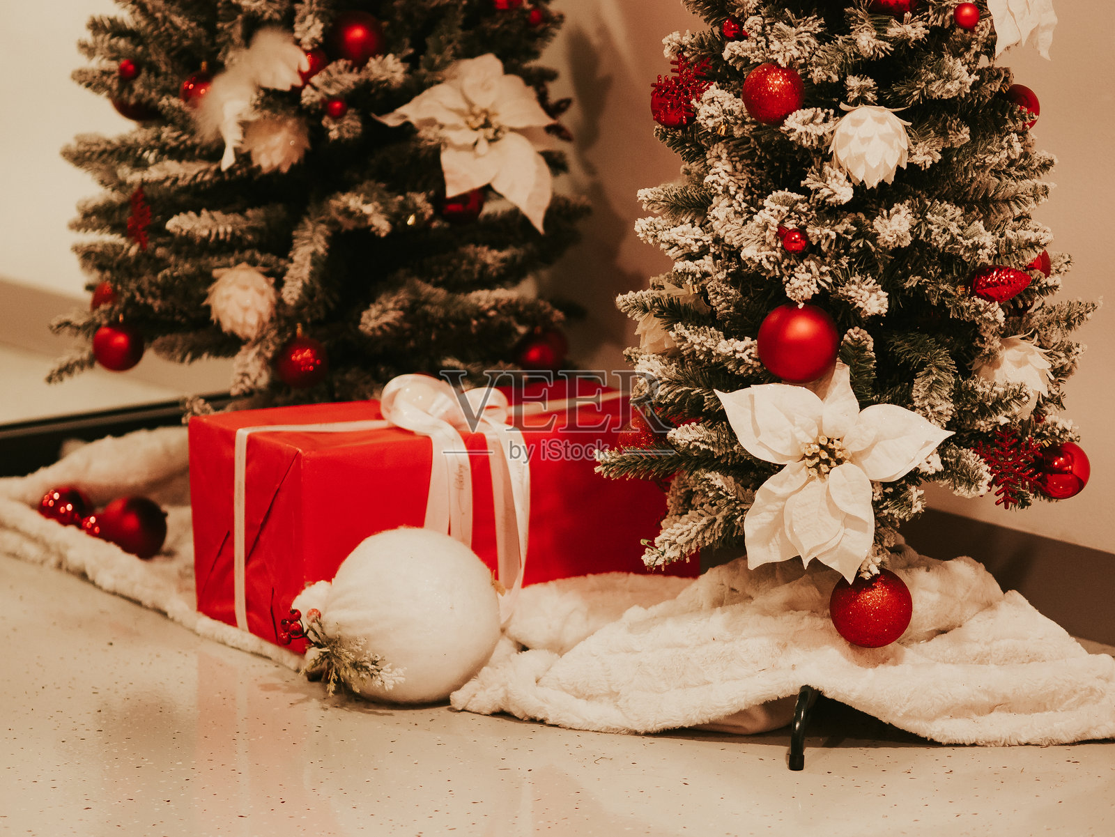 红色礼品盒用白色缎带系成蝴蝶结。礼物放在树下。人造圣诞树的树枝上装饰着圣诞树饰品。新年庆祝概念。2024年12月31日 - 克罗地亚普拉照片摄影图片