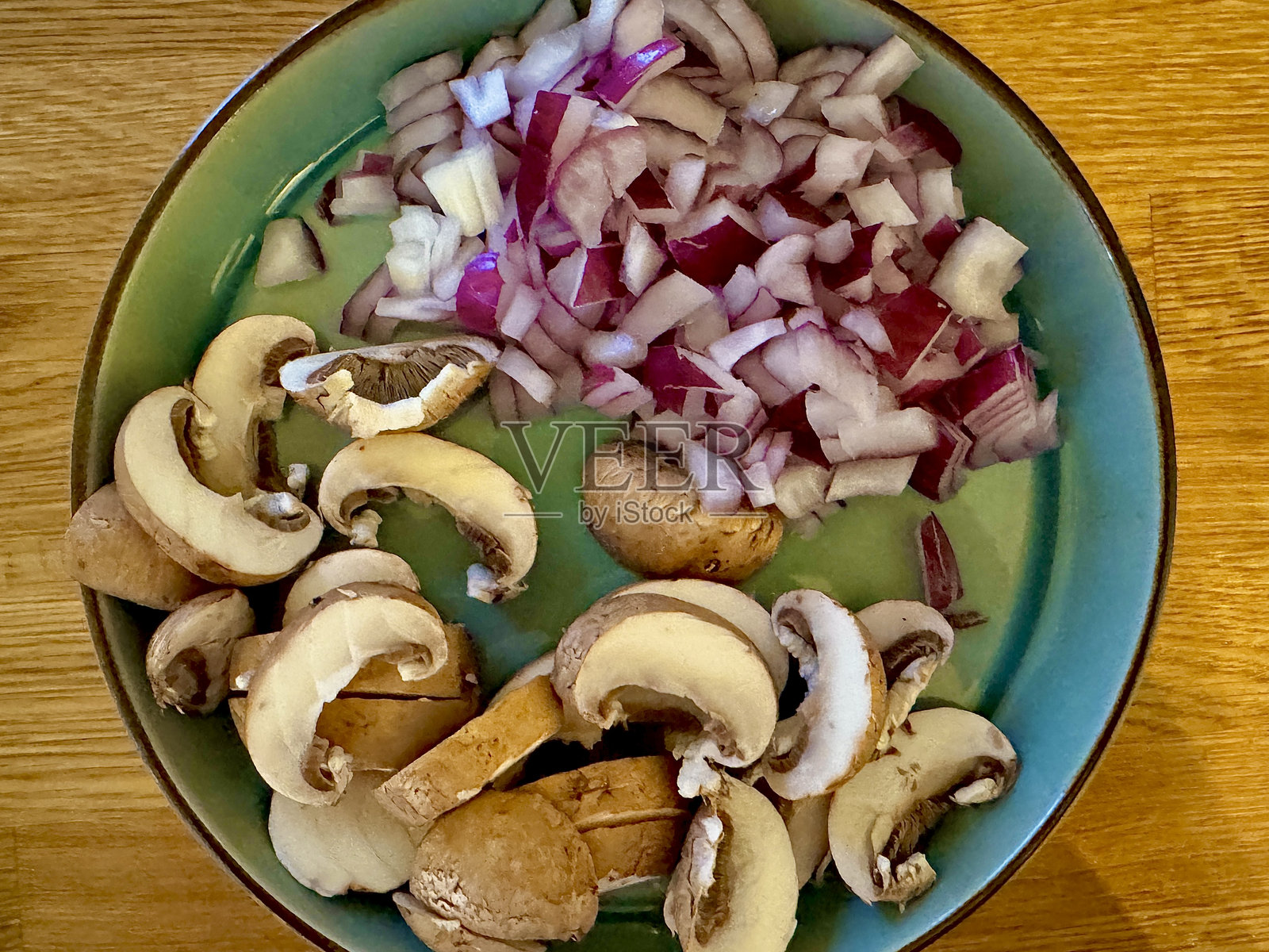 一个绿色的盘子里放着切好的红洋葱和切片的蘑菇，正在准备食材。照片摄影图片