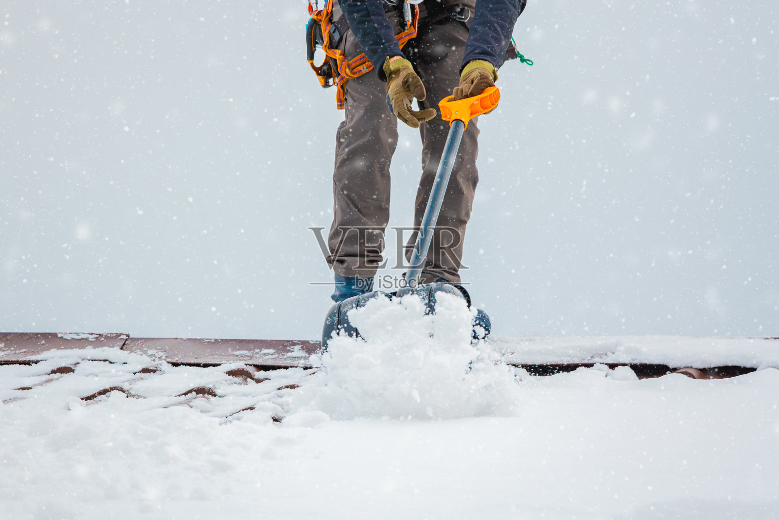 社区服务工人工业攀登者在冬季清除建筑屋顶上的雪。在俄罗斯莫斯科，雪暴过后清理城市街道、道路和建筑屋顶。照片摄影图片
