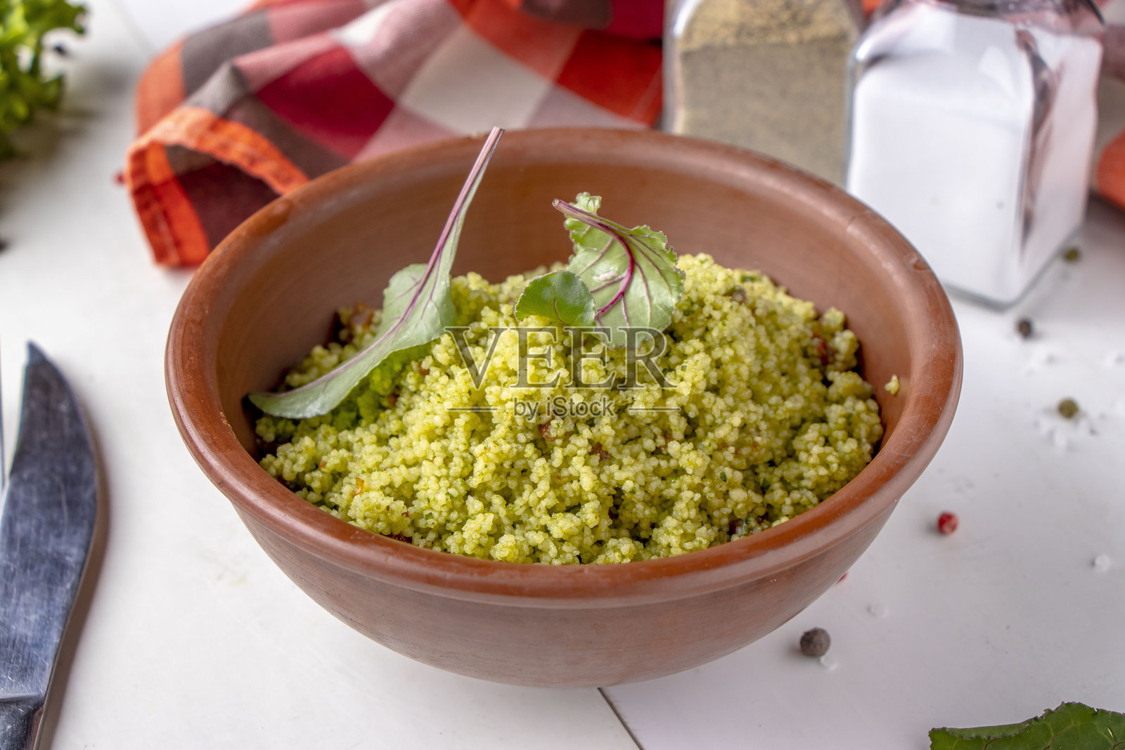 白色背景上的碗里装着库斯库斯，配有橄榄油和干番茄照片摄影图片