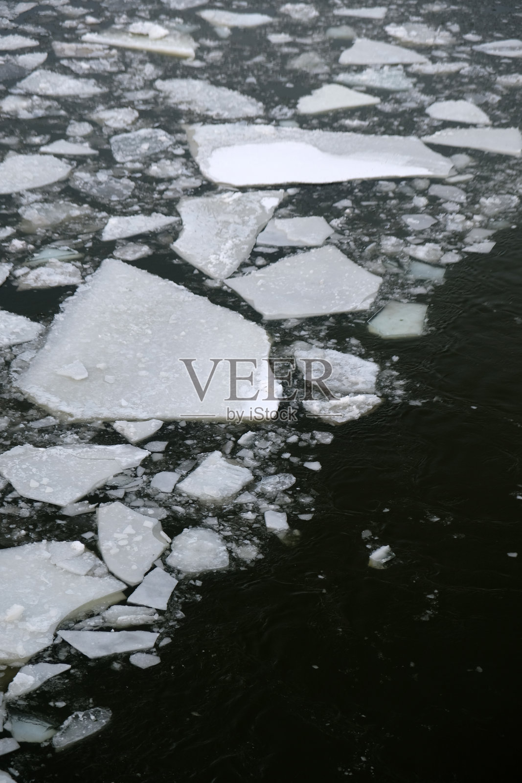 一张水体的照片，黑色的水面被一部分有冰和没有冰的区域对角线分割。照片摄影图片