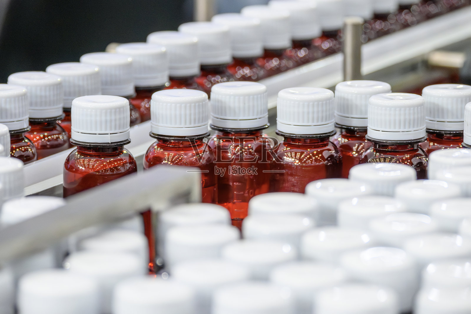 传送带上的红色药瓶正在进行灌装过程。照片摄影图片