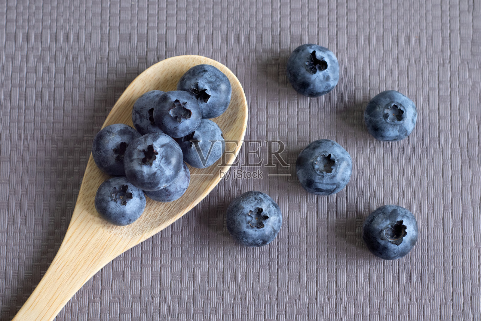 木勺中的有机蓝莓，背景为灰色纹理，正面视角。素食、新鲜、天然食品的概念。照片摄影图片