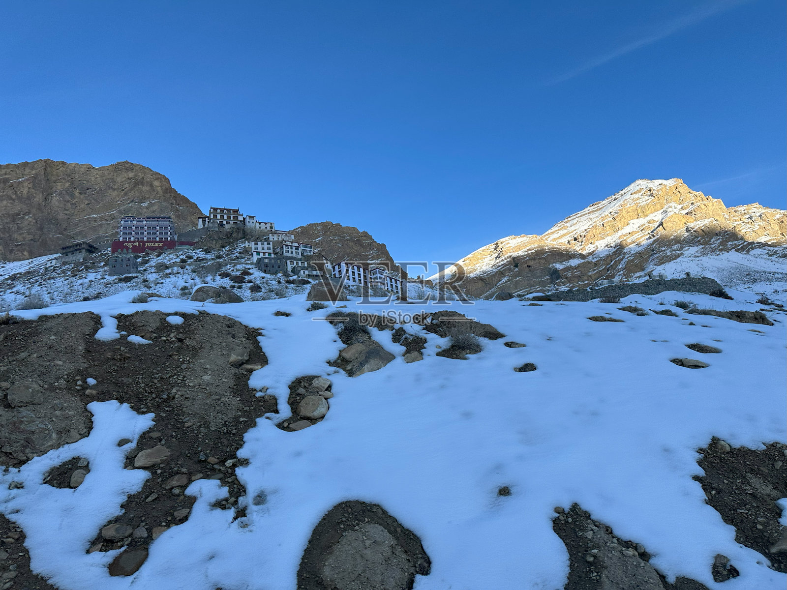 雪-covered山道上的基寺，通往阳光明媚的风景谷地，蓝天清澈。照片摄影图片