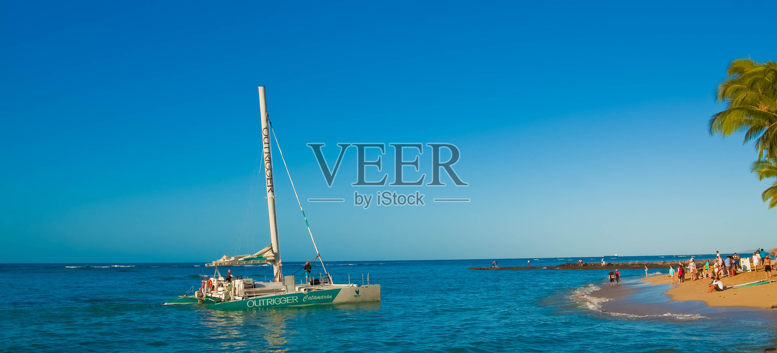 在威基基海滩接载乘客的双体船照片摄影图片