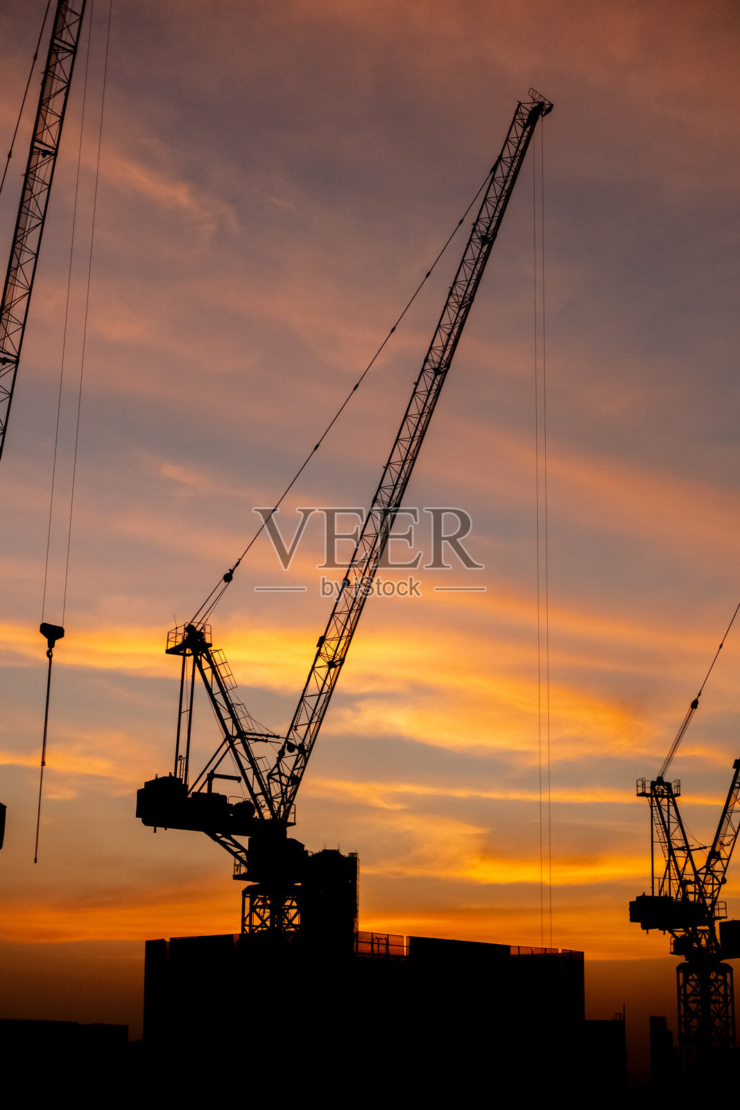 建筑起重机的剪影与美丽的日落天空。照片摄影图片