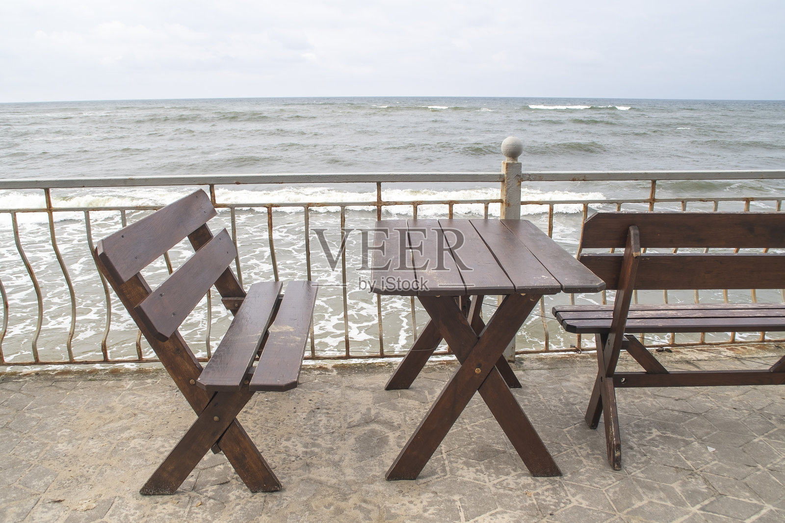 海边街咖啡馆的空桌椅。海堤上的寒冷天气。照片摄影图片
