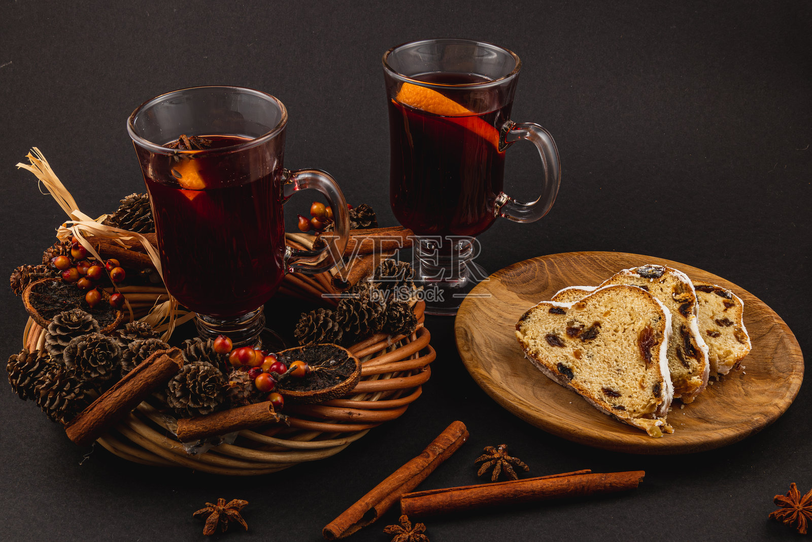 香料热红酒与新鲜的斯托伦蛋糕放在黑色背景上的木盘上照片摄影图片