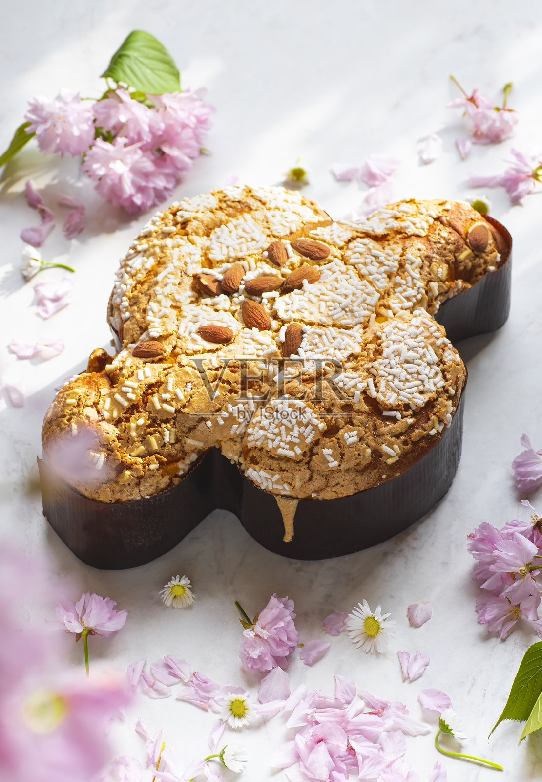 意大利复活节甜面包或蛋糕，配有杏仁、糖粉和糖渍水果的复活节鸽子。烘焙的鸽子是基督和复活节的象征，粉色花朵。明亮的光线，自然风格。照片摄影图片