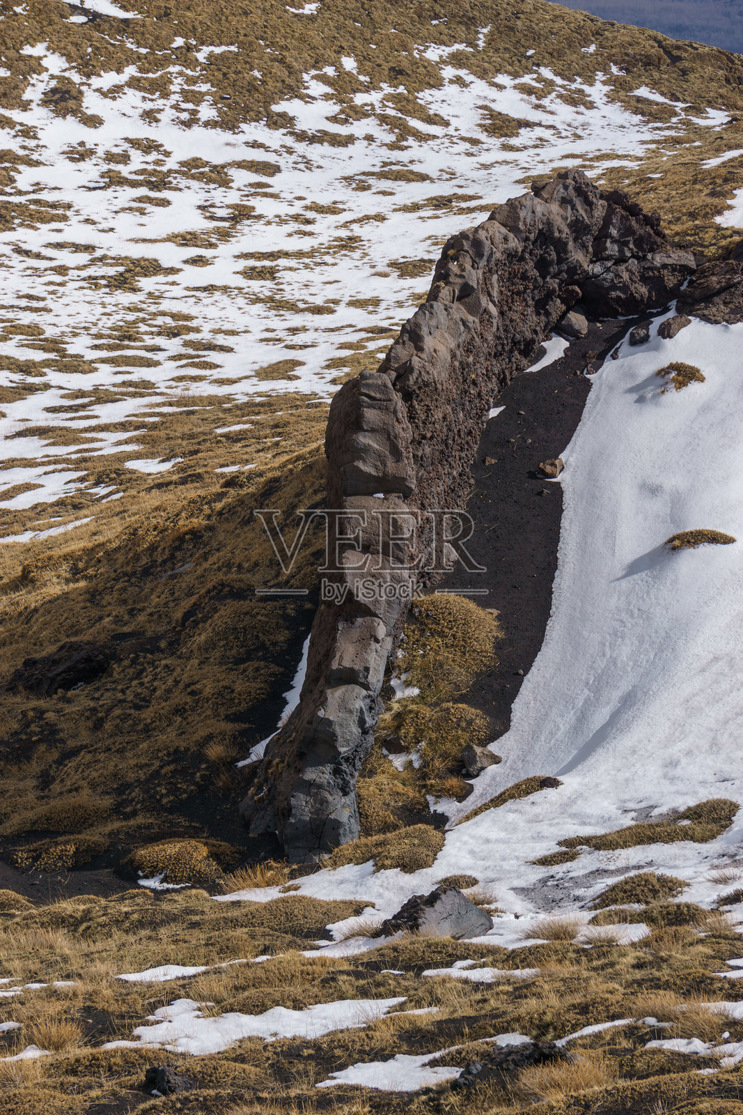 西西里岛卡塔尼亚的埃特纳火山奇特的岩石形成，黑色熔岩与黄色草地在阴云密布的冬日中交织。照片摄影图片