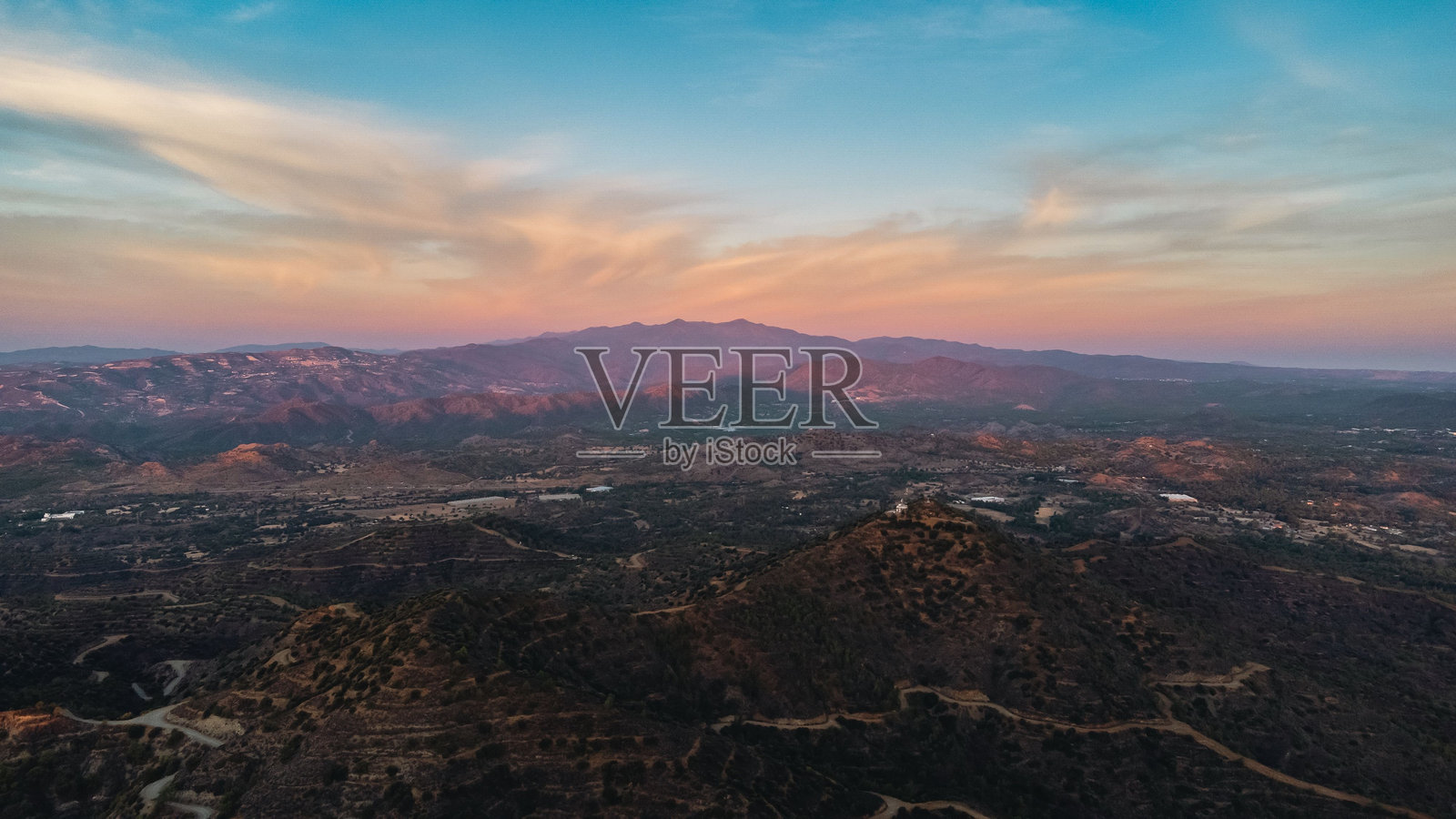 日落天空与起伏山丘的航拍风景。照片摄影图片