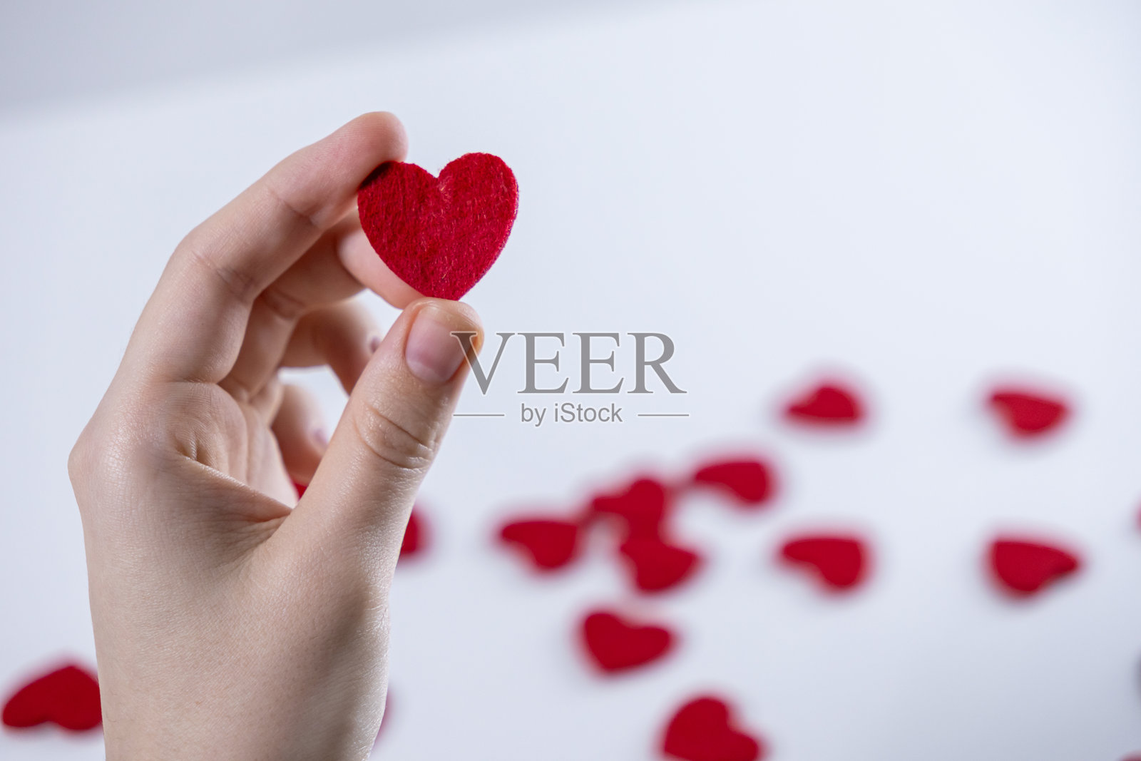 手握红色心形符号，象征爱情、浪漫、情感、关怀，白色背景装饰，激情浪漫的姿态，聚焦孤立。照片摄影图片