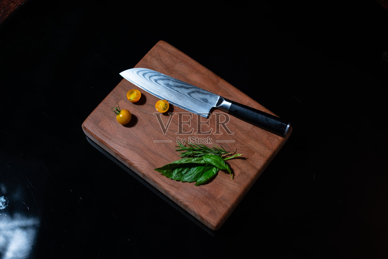 黑色背景上的枫木切菜板，配有番茄和薄荷叶装饰照片摄影图片