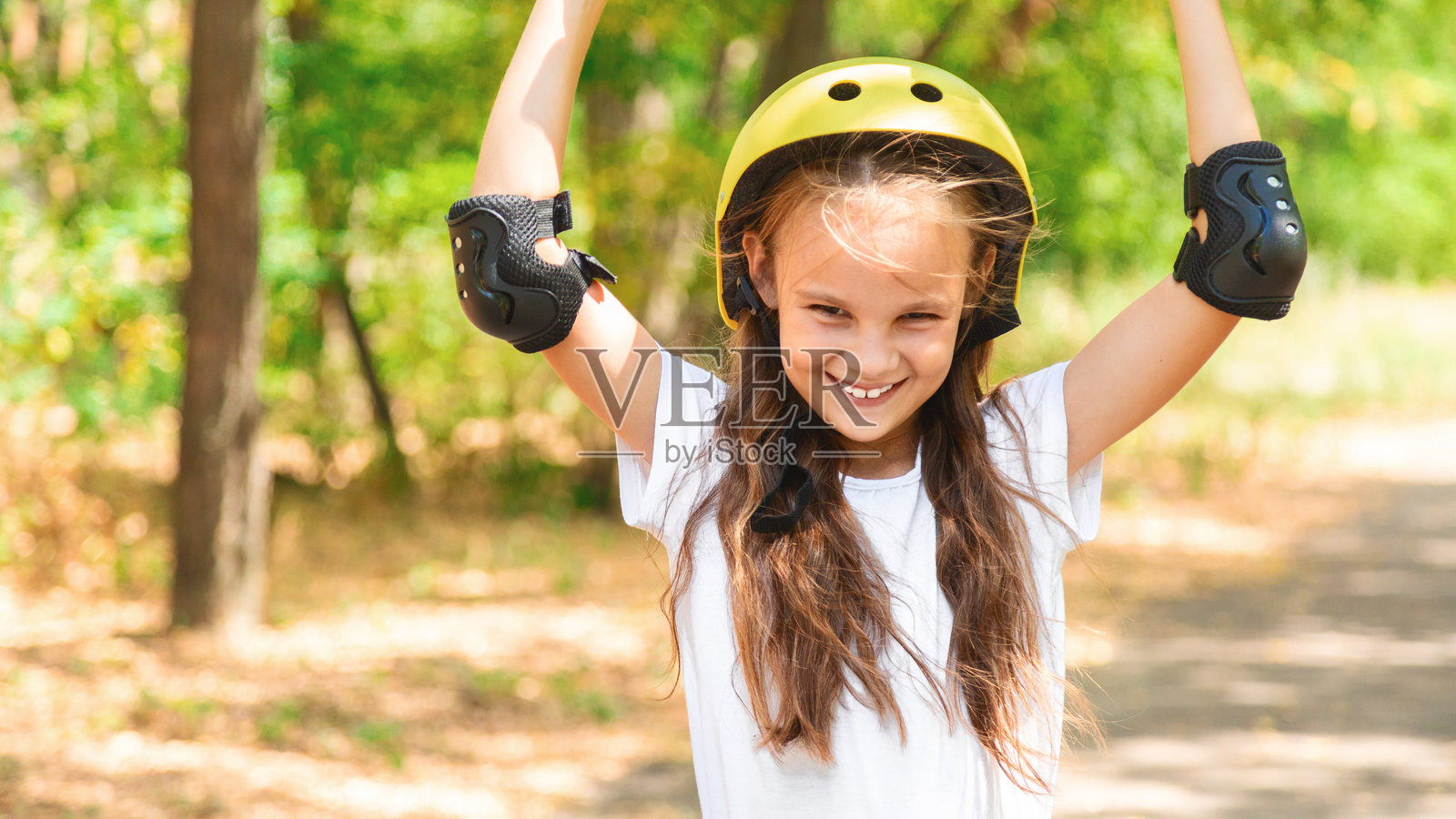 女孩滑板，佩戴安全装备 - 头盔、护膝和护肘。安全的夏季活动。儿童活动。照片摄影图片