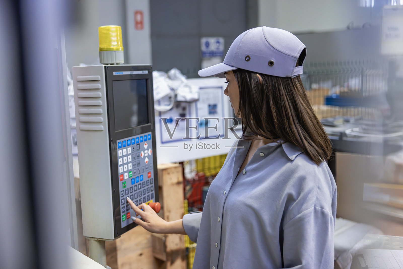 专注的年轻女性工人/工程师在工厂的电脑显示器前。照片摄影图片