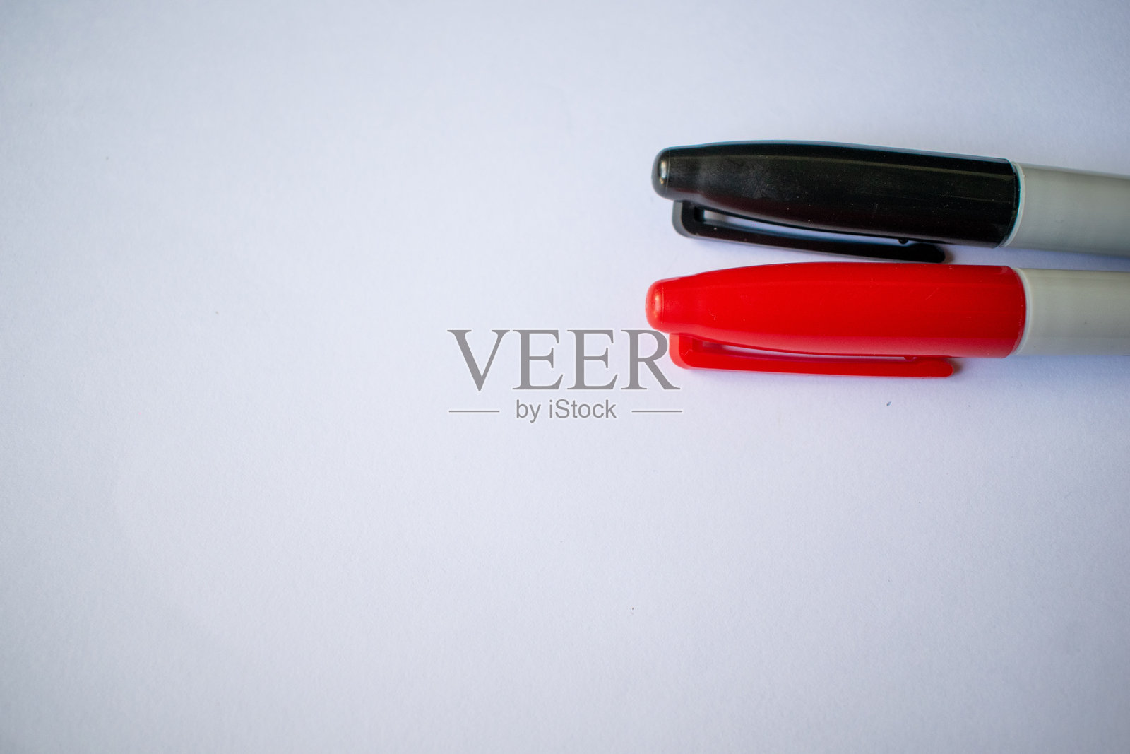 白色表面上的红色和黑色马克笔照片摄影图片