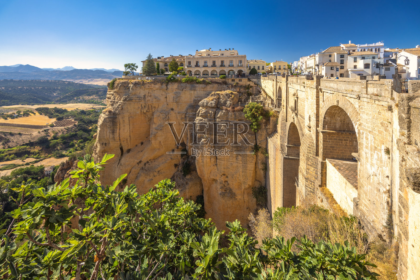 西班牙隆达镇的塔霍峡谷中的普恩特纽沃桥。古老的桥梁横跨深峡谷，村庄高高坐落在悬崖边上。阳光明媚，风景如画。照片摄影图片