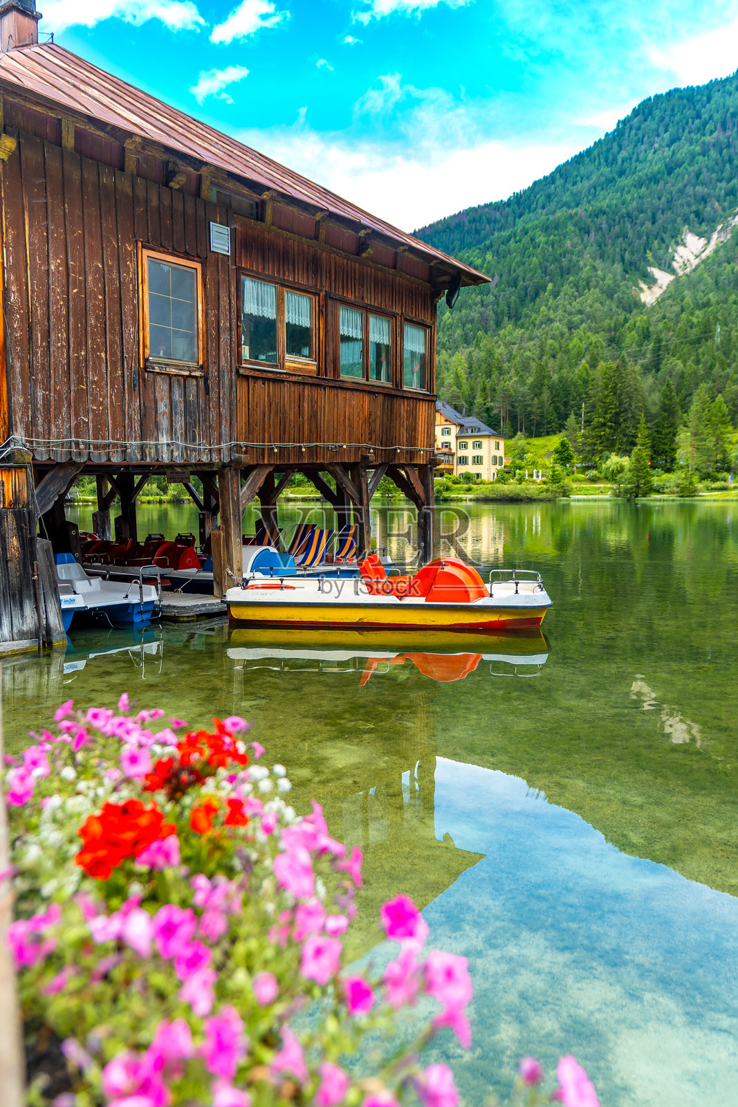 多洛米蒂山脉的多比亚科湖边停靠的脚踏船在木屋下。照片摄影图片