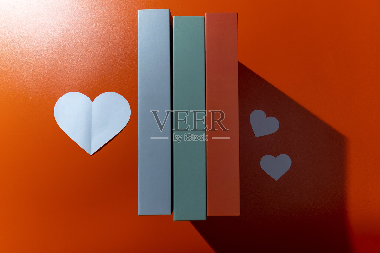 白色心形图案与一排书籍在彩色背景上的俯视图照片摄影图片