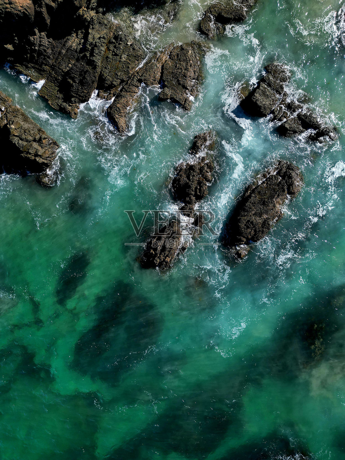 海浪拍打岩石海岸的鸟瞰图。照片摄影图片