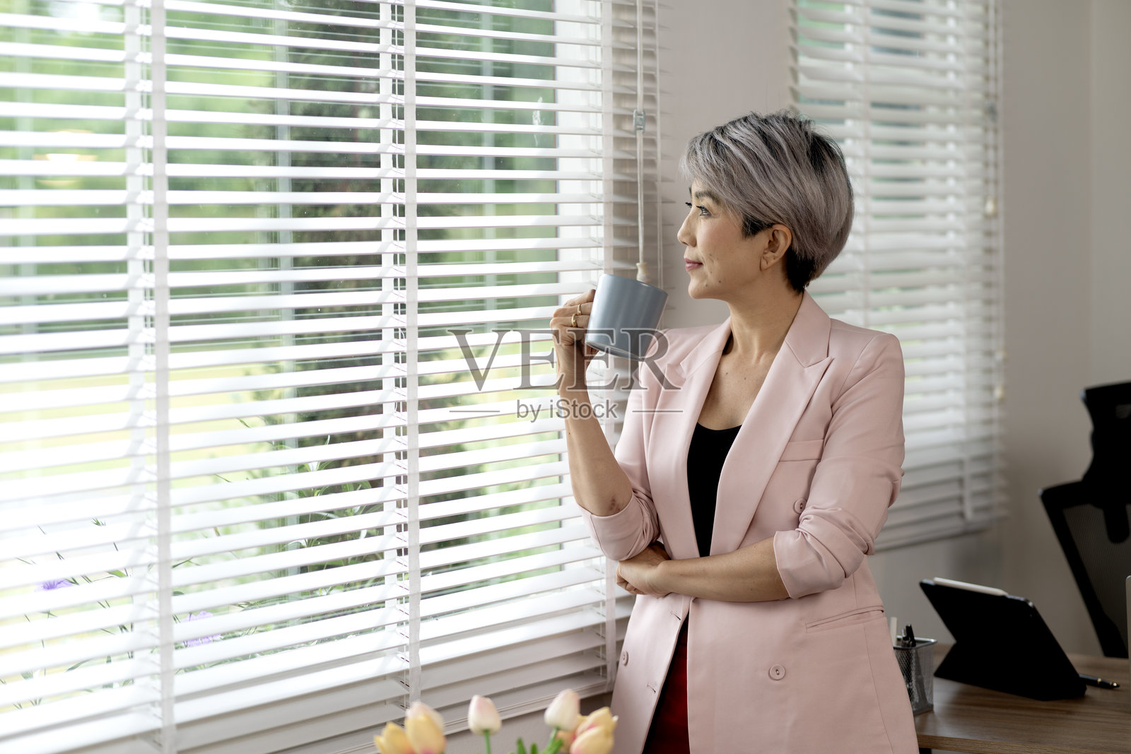 穿着休闲服的资深女商人手里拿着一个咖啡杯照片摄影图片