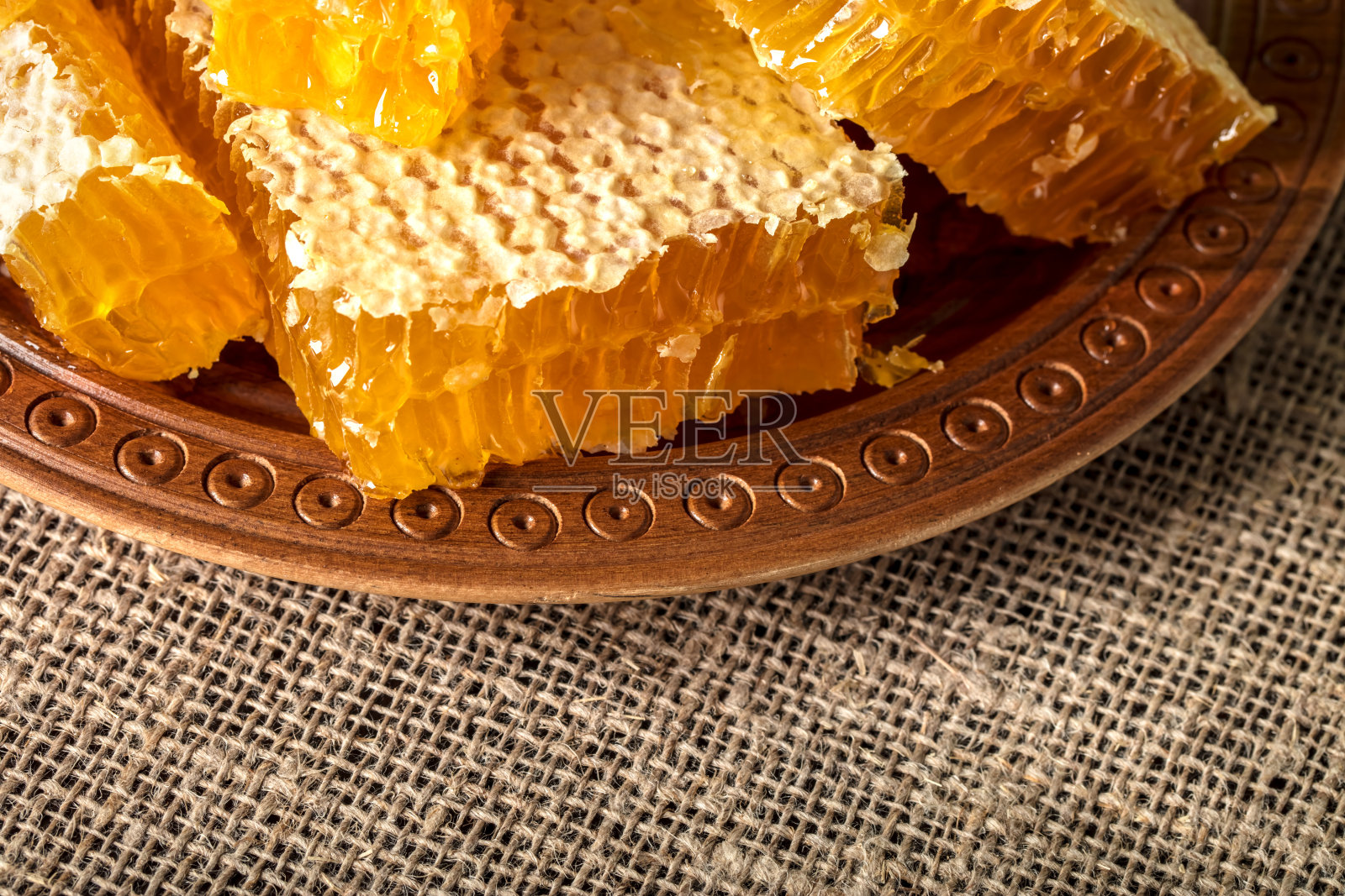 新鲜切好的蜂巢片，里面装满了蜂蜜，放在木盘上照片摄影图片