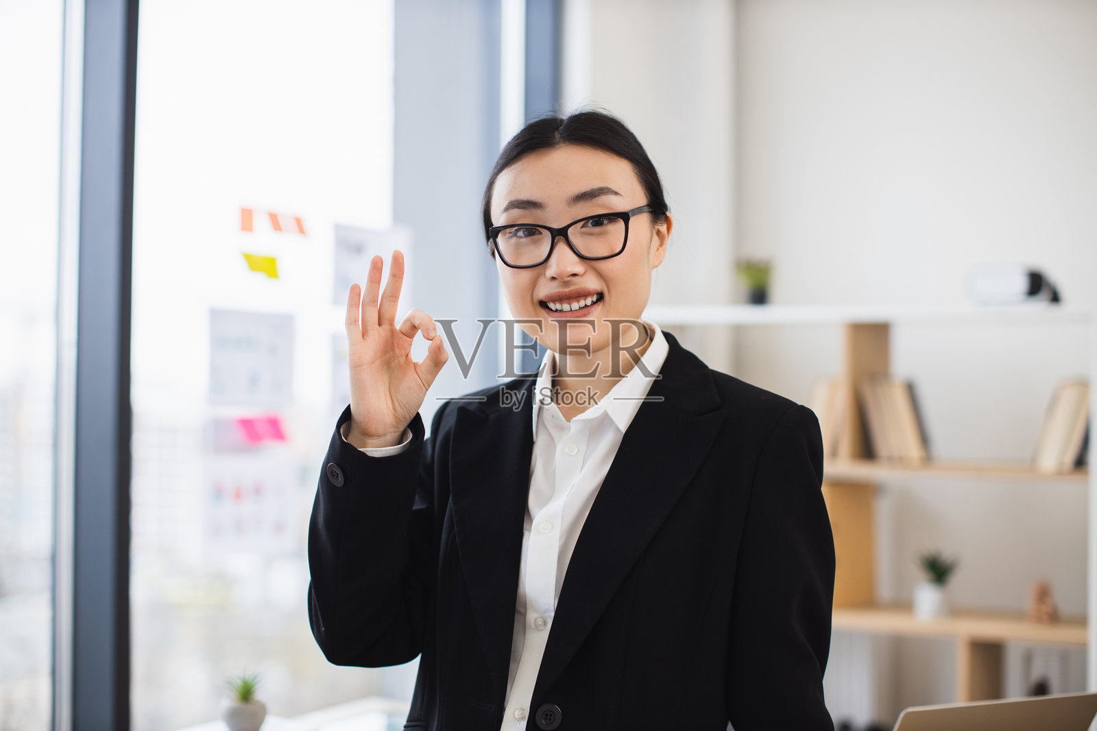 自信的年轻亚洲女商人在办公室环境中做出“好的”手势照片摄影图片