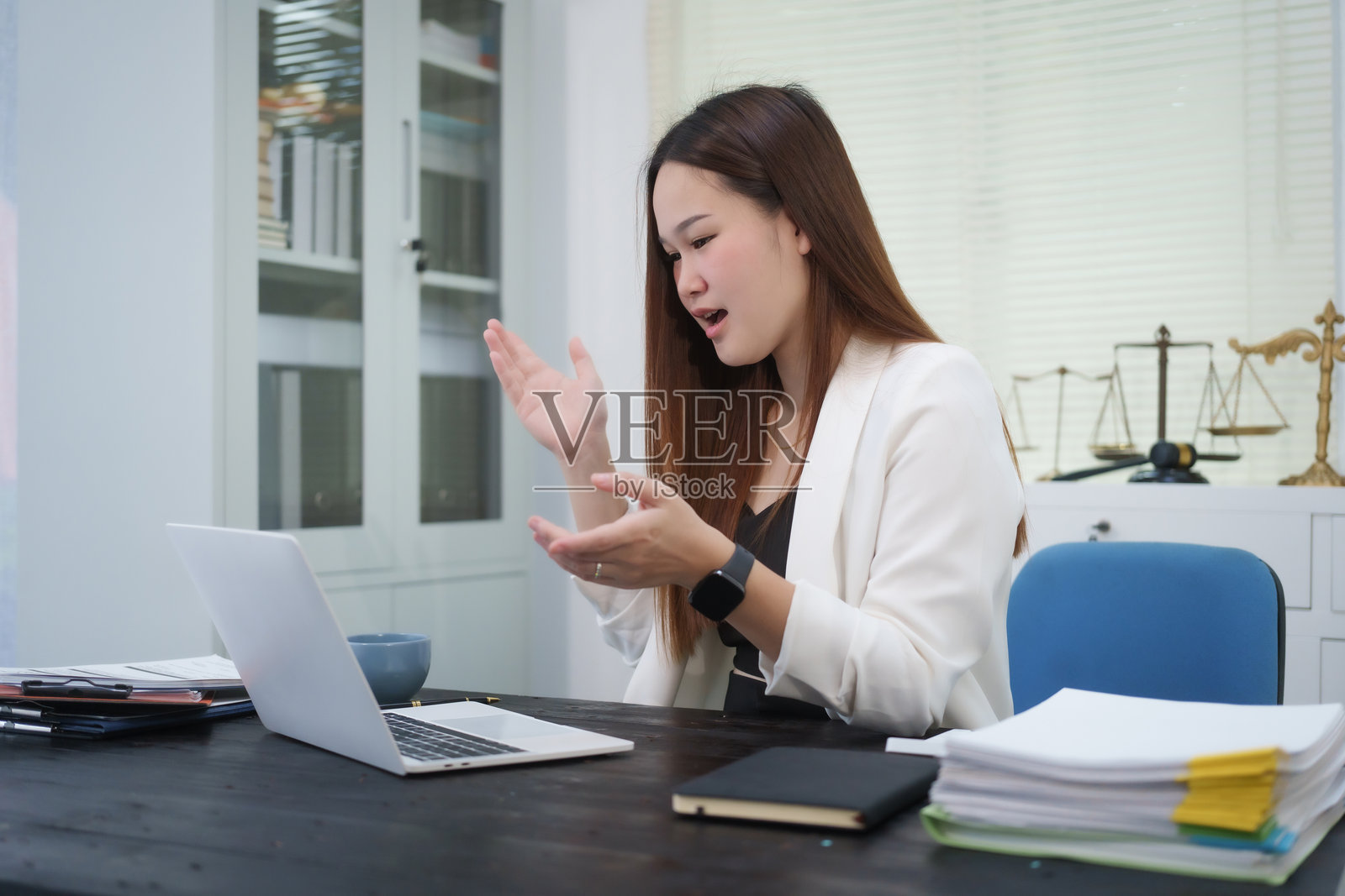 一位年轻的职业女性在办公室的桌子前工作，提供在线法律咨询，处理民事纠纷案件，包括诉讼、贷款违约、不公正解雇和财产问题。照片摄影图片