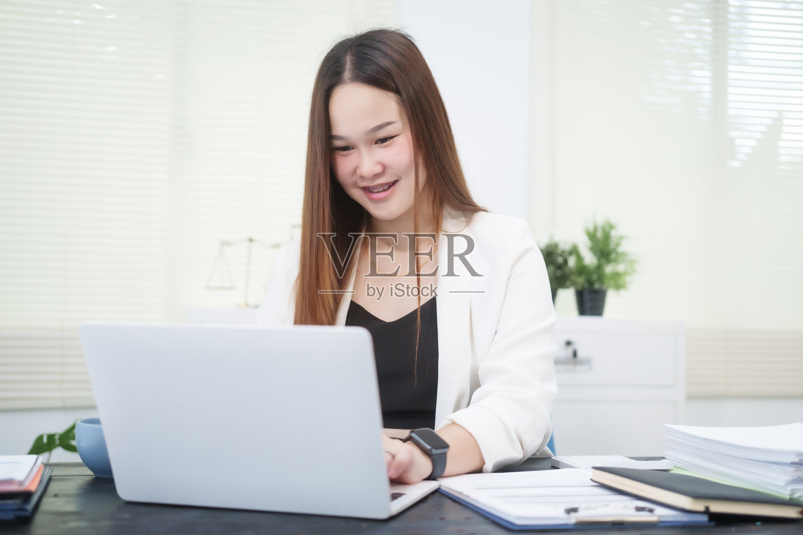 一位年轻的职业女性在办公室的桌子前工作，提供在线法律咨询，处理民事纠纷案件，包括诉讼、贷款违约、不公正解雇和财产问题。照片摄影图片