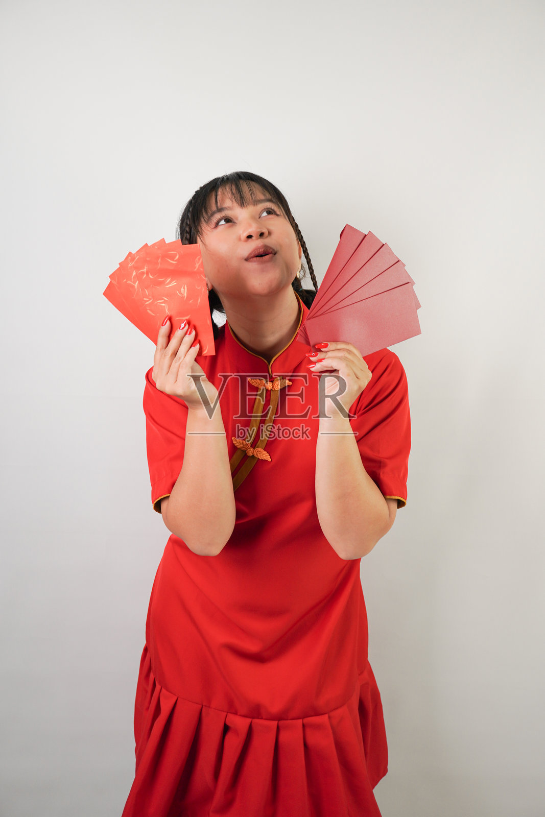 微笑的年轻亚洲女性穿着红色传统中国服装，手里拿着许多红包，背景为白色。适合春节派对的概念。照片摄影图片