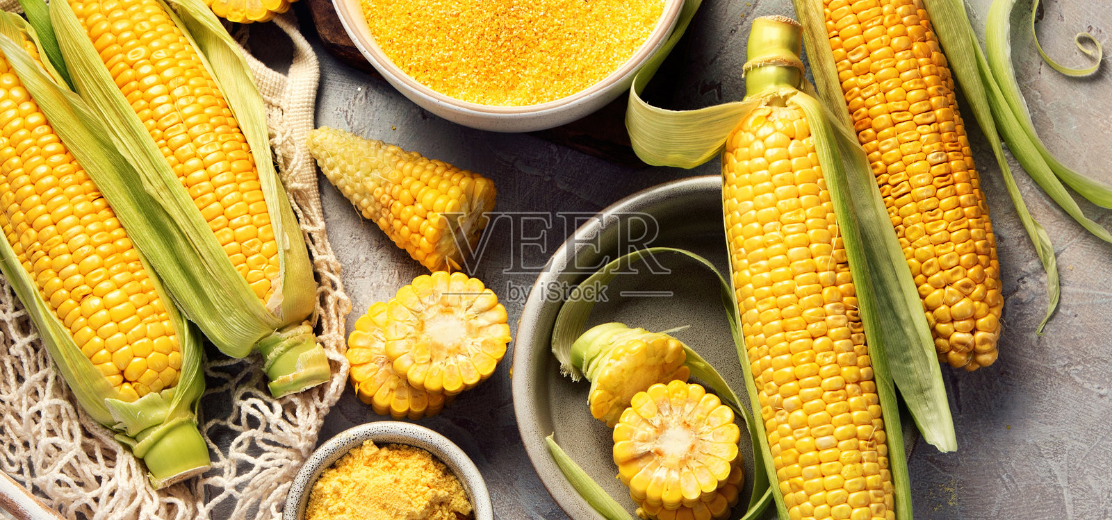 玉米棒和玉米粒在灰色背景上。照片摄影图片